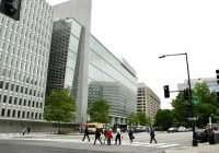 A group of people walking across a street next to tall buildings