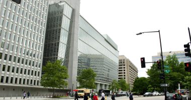A group of people walking across a street next to tall buildings